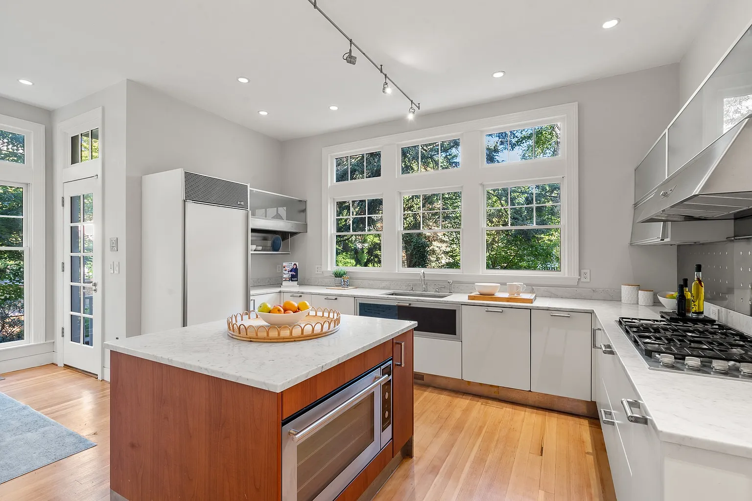 Kitchen with Poggenpohl cabinetry, pale stone counters, and contemporary appliances, while a central island now organizes the main work area beneath the windows.