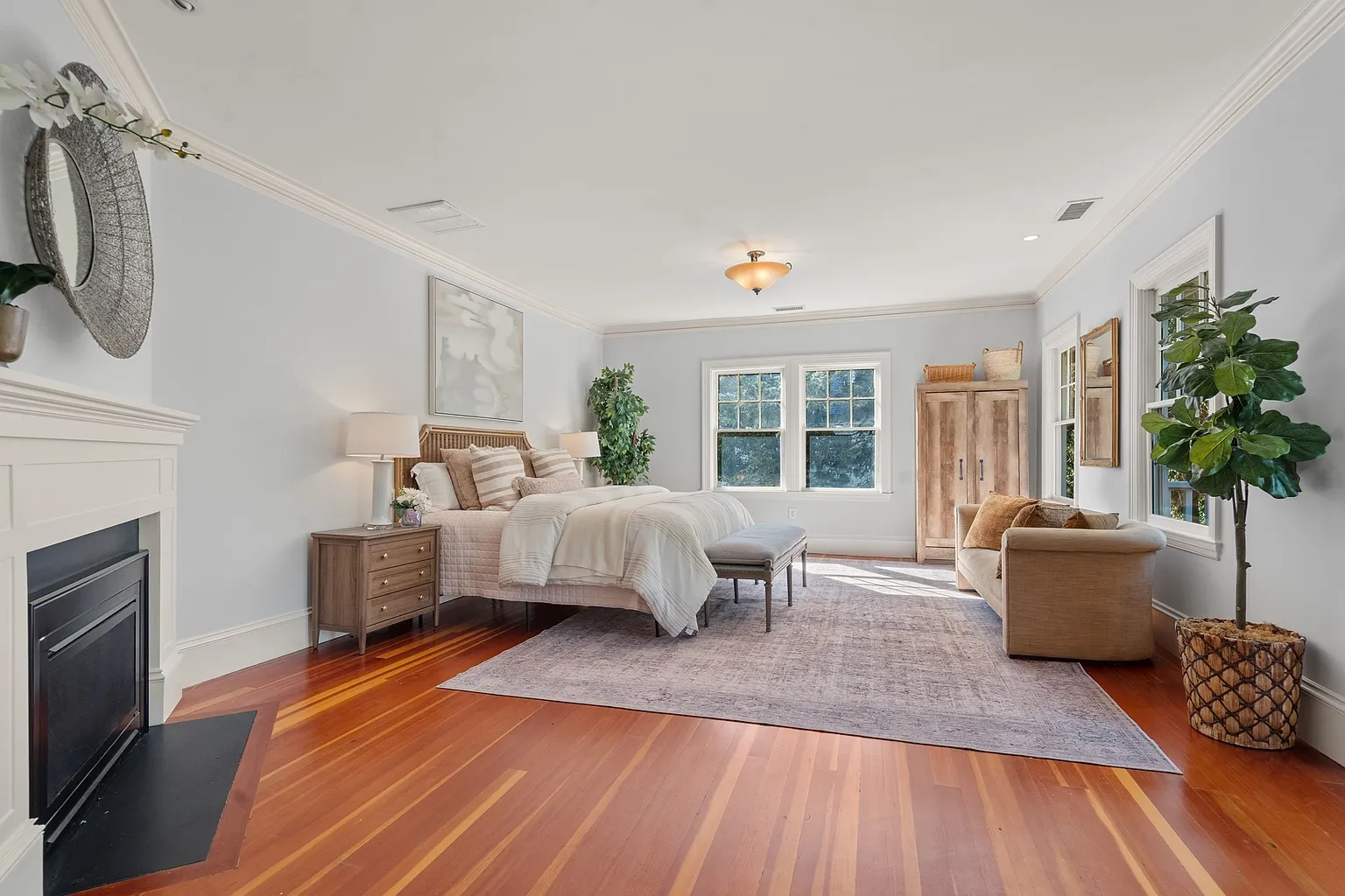 The primary suite opens into a spacious bedroom with a gas fireplace set along one wall and windows bringing in light from multiple sides. 