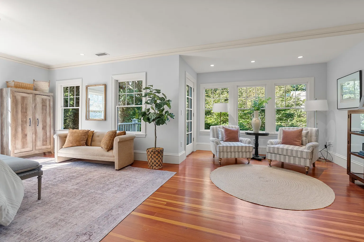 The sleeping area extends into its own sitting room, where a pair of cushioined chairs is placed next to a glass door leading to a private balcony.
