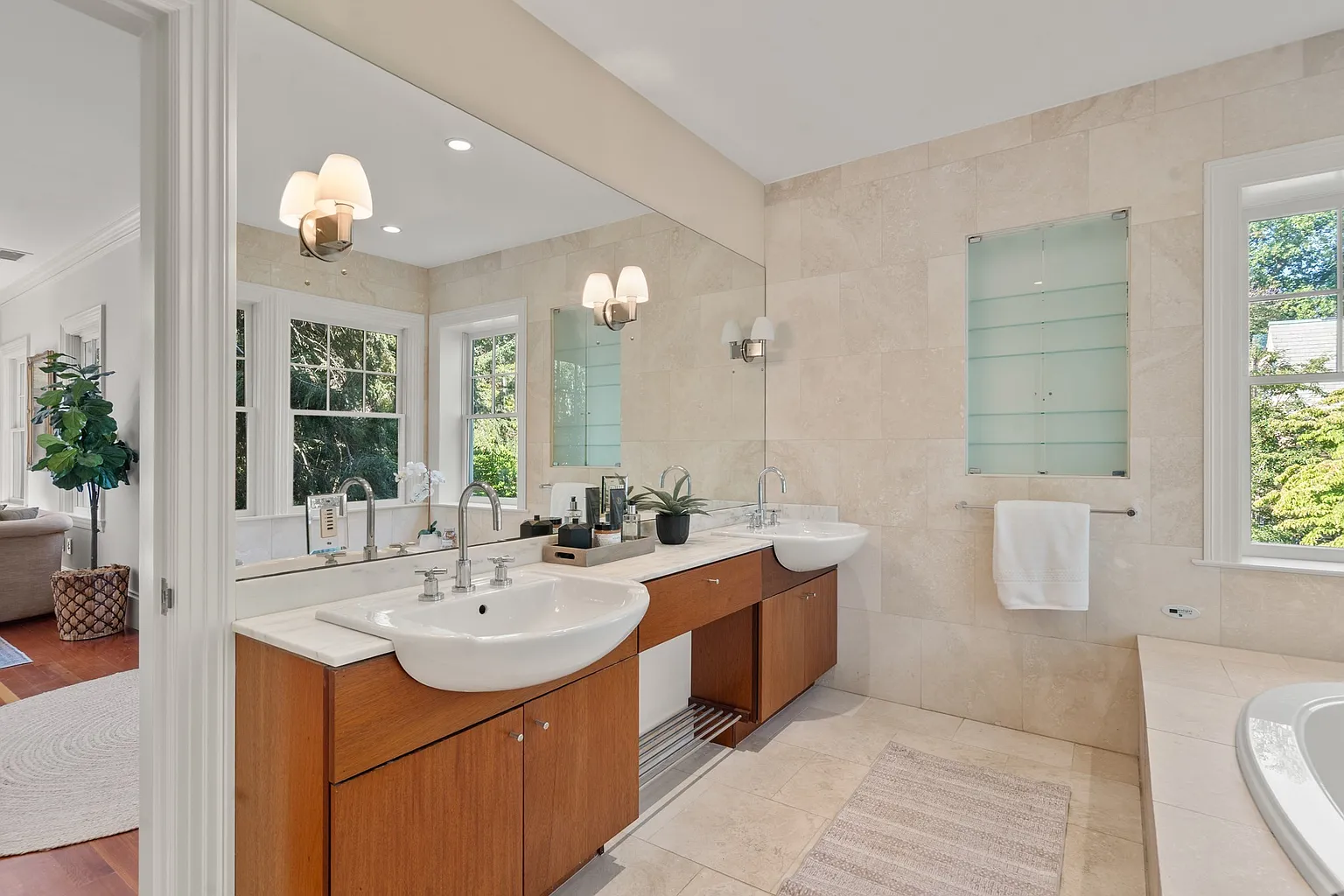 A long double vanity with wood cabinetry and round sinks sit beneath a full-width mirror. 