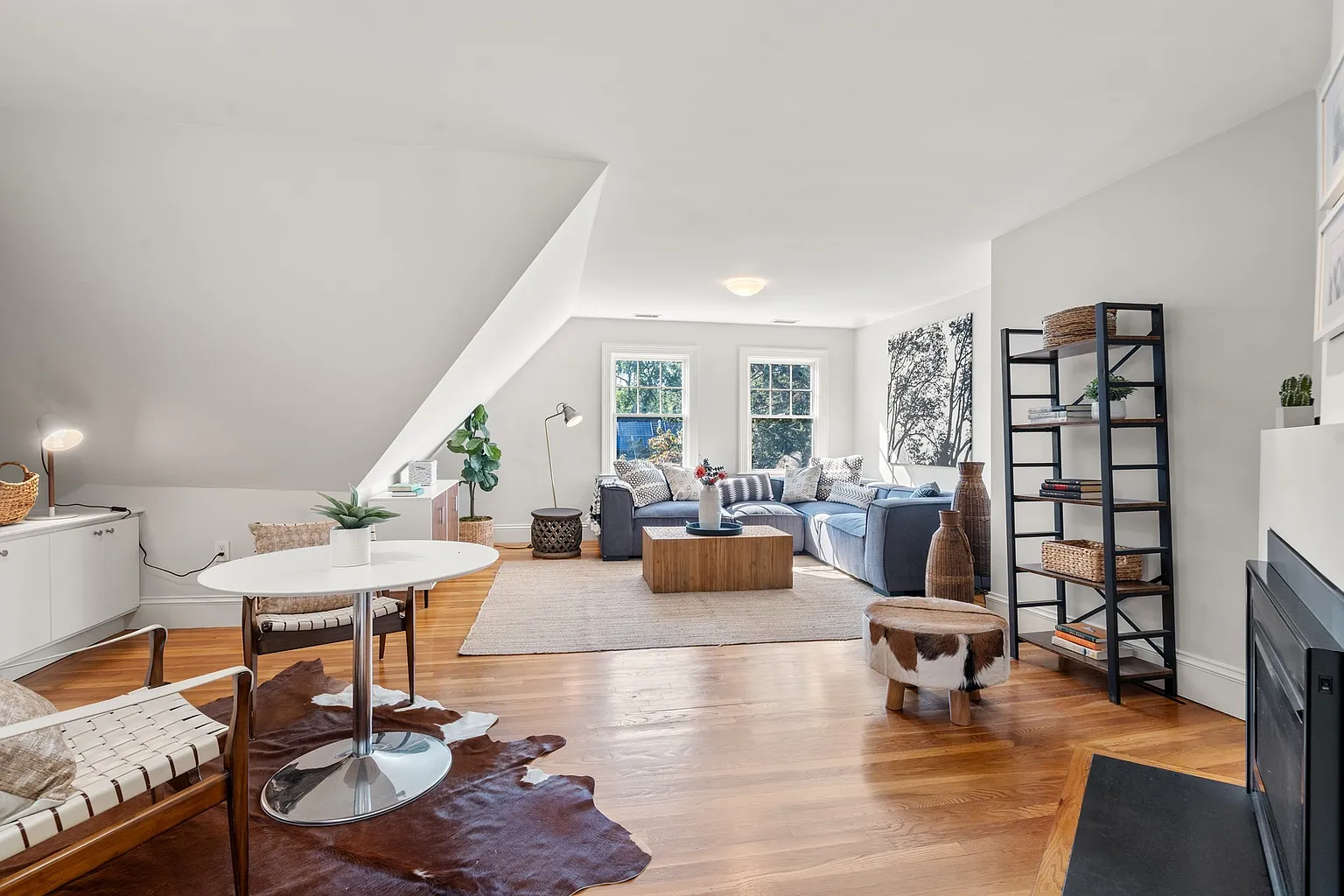 The room opens wide from the landing, with wood floors running through a sitting area gathered around an L-shaped couch at the far end.