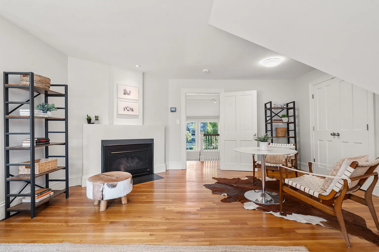 Closer to the stairs, a smaller table sits across from a fireplace creating a second spot for reading or work.