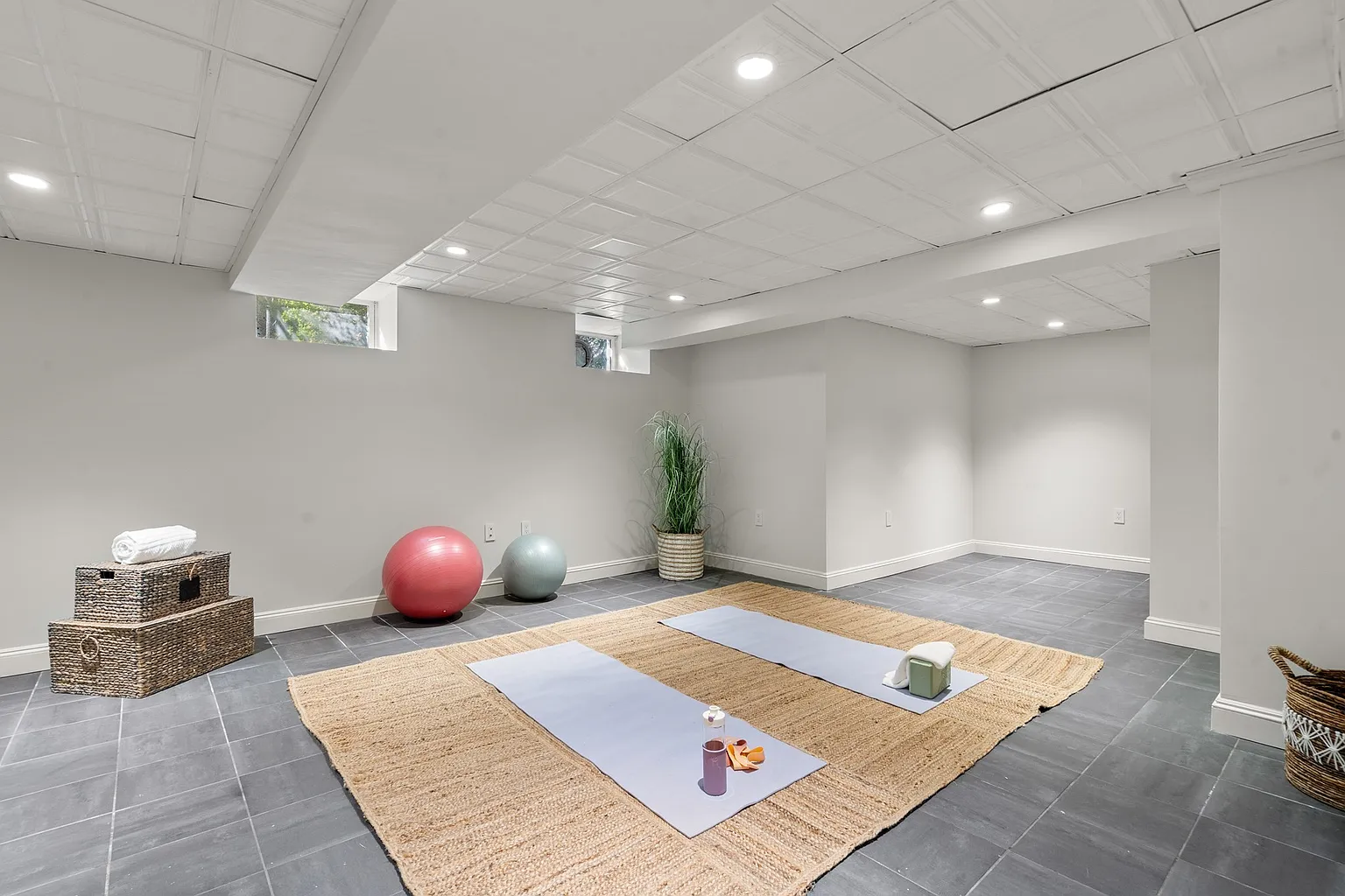 The yoga and fitness room with tiled floors and recessed lighting creating a simple backdrop for exercise or stretching.