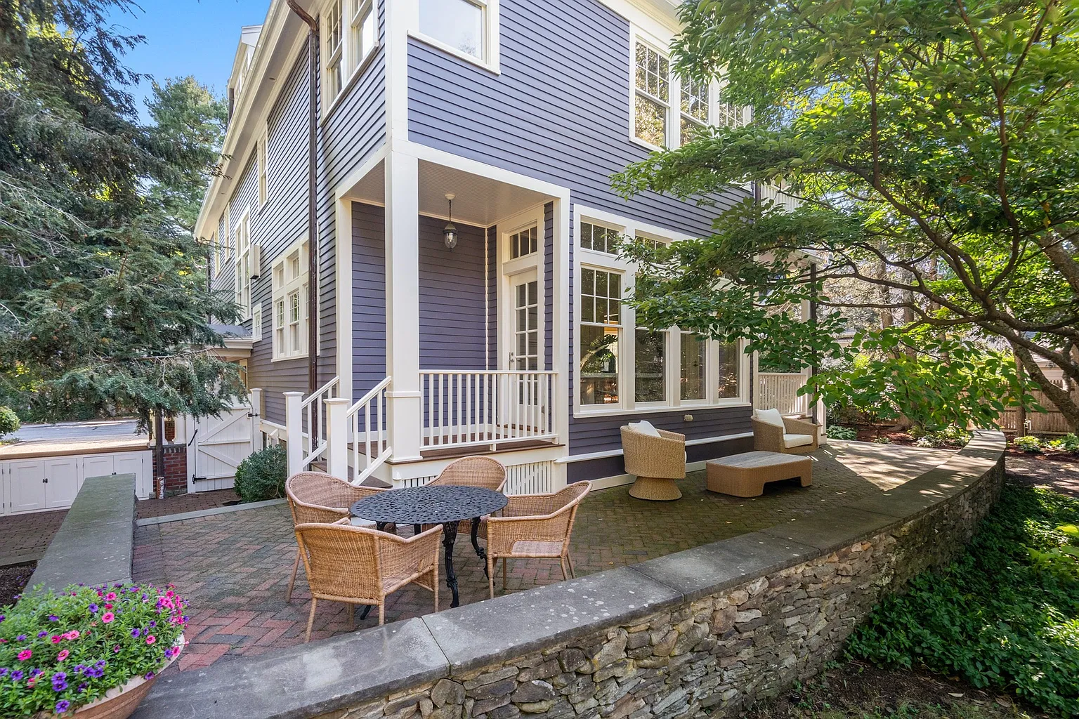 An expansive brick patio sits against the back of the house, raised above the surrounding gardens by low stone retaining walls.