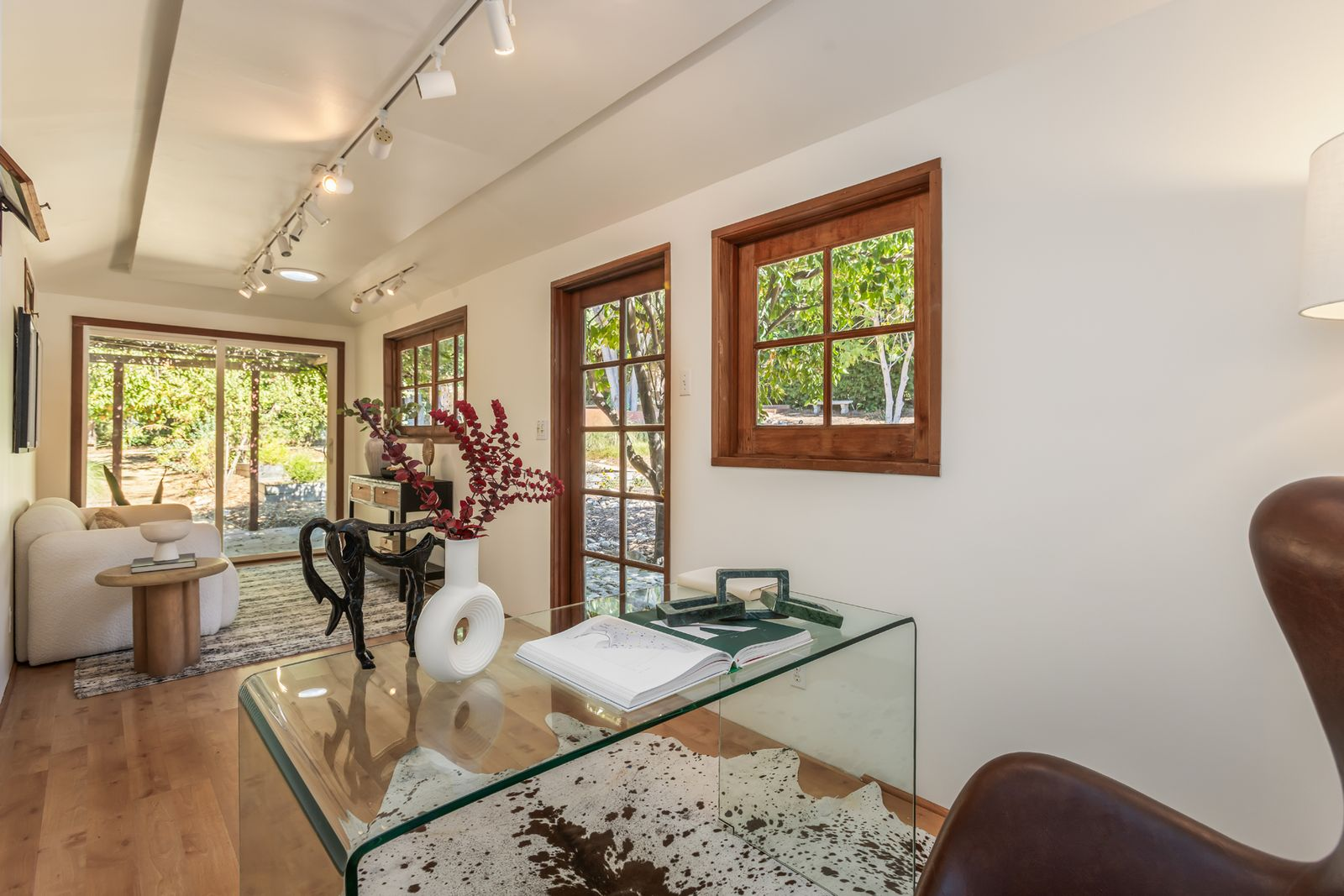 Track lighting follows the length of the ceiling, while the open plan leaves room for a desk at one end and a small sitting area near the glass doors.