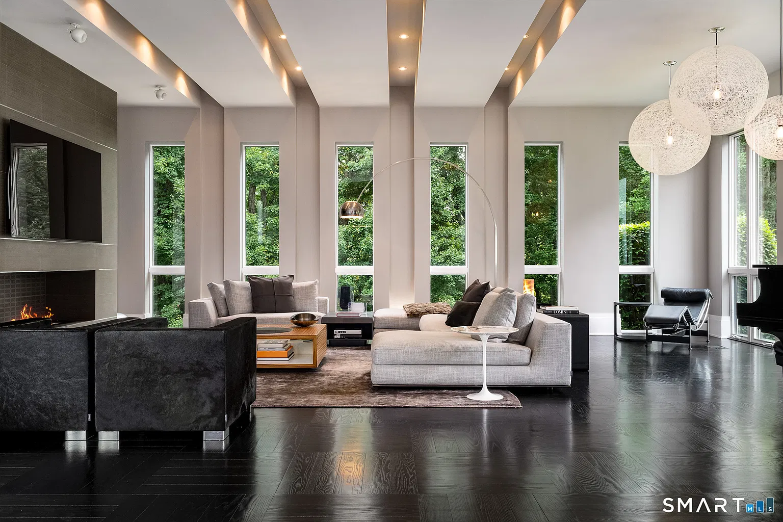 The living room opens beneath tall ceilings, with a series of narrow floor-to-ceiling windows stretching along the exterior wall.