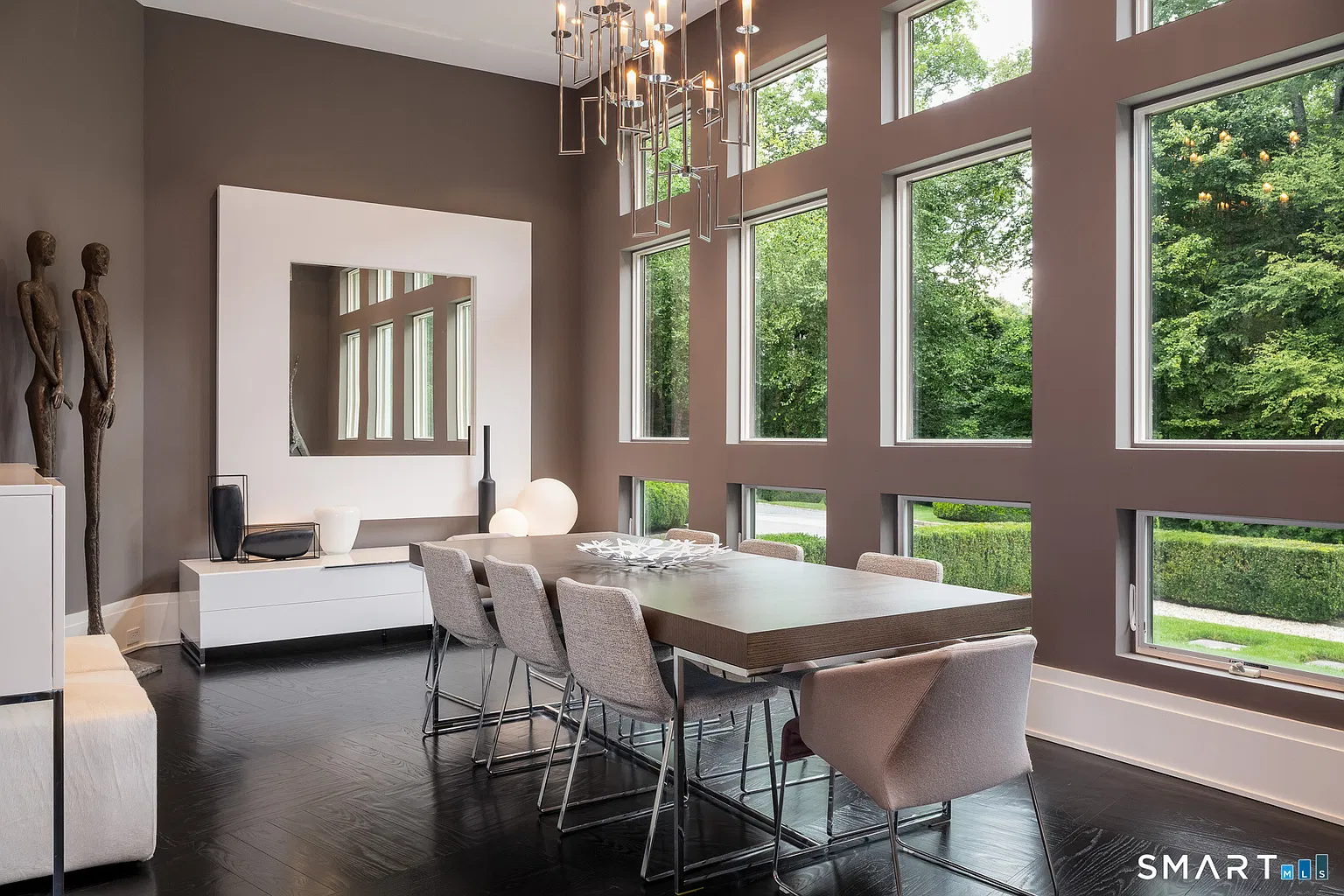 The large dining table sits directly beneath a sculptural chandelier that drops into the center of the room.