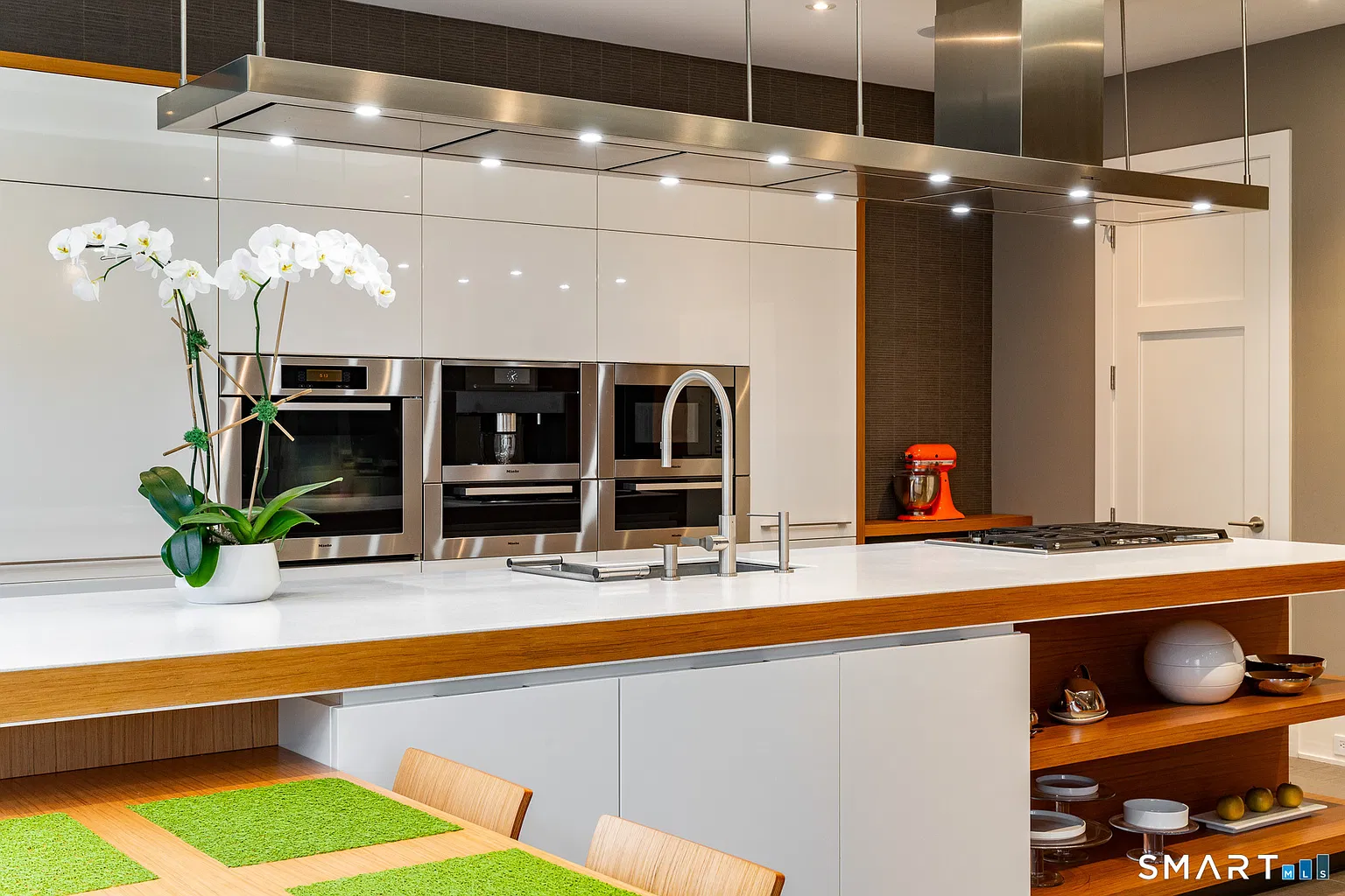Poliform cabinetry wraps the back wall in glossy white panels around integrated stainless-steel appliances.