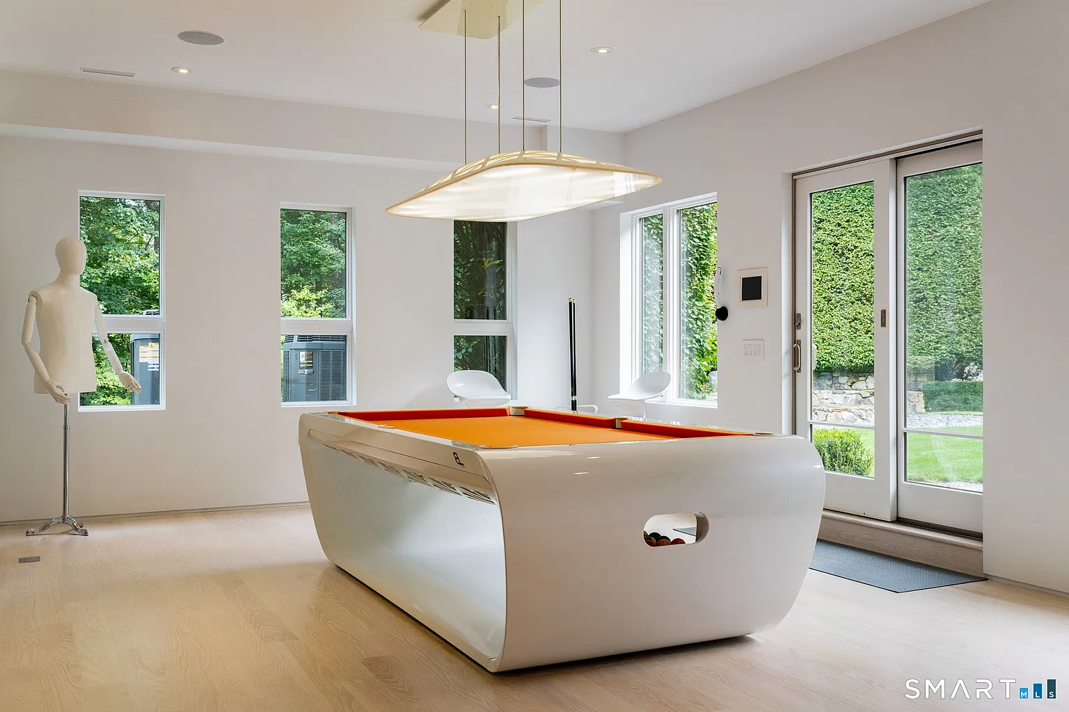 A billiards room centered on a curved white pool table with an orange playing surface. 