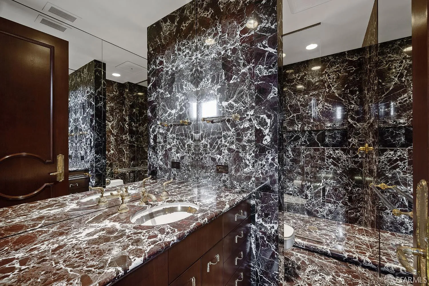 The suite's bathroom has dark veined marble covering the vanity, walls, and shower. 