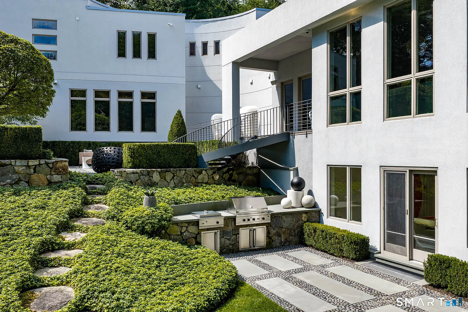 A level below, another terrace is tucked against the lower level of the house with a built-in outdoor kitchen set into a stone wall.