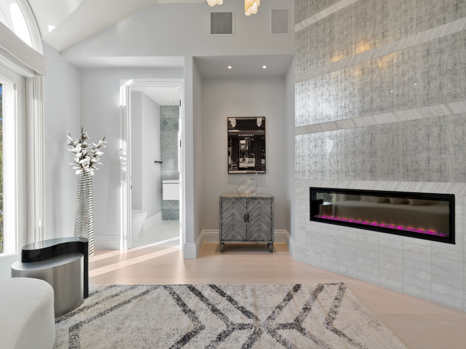 A separate sitting lounge with a long linear fireplace set into a full-height textured wall.