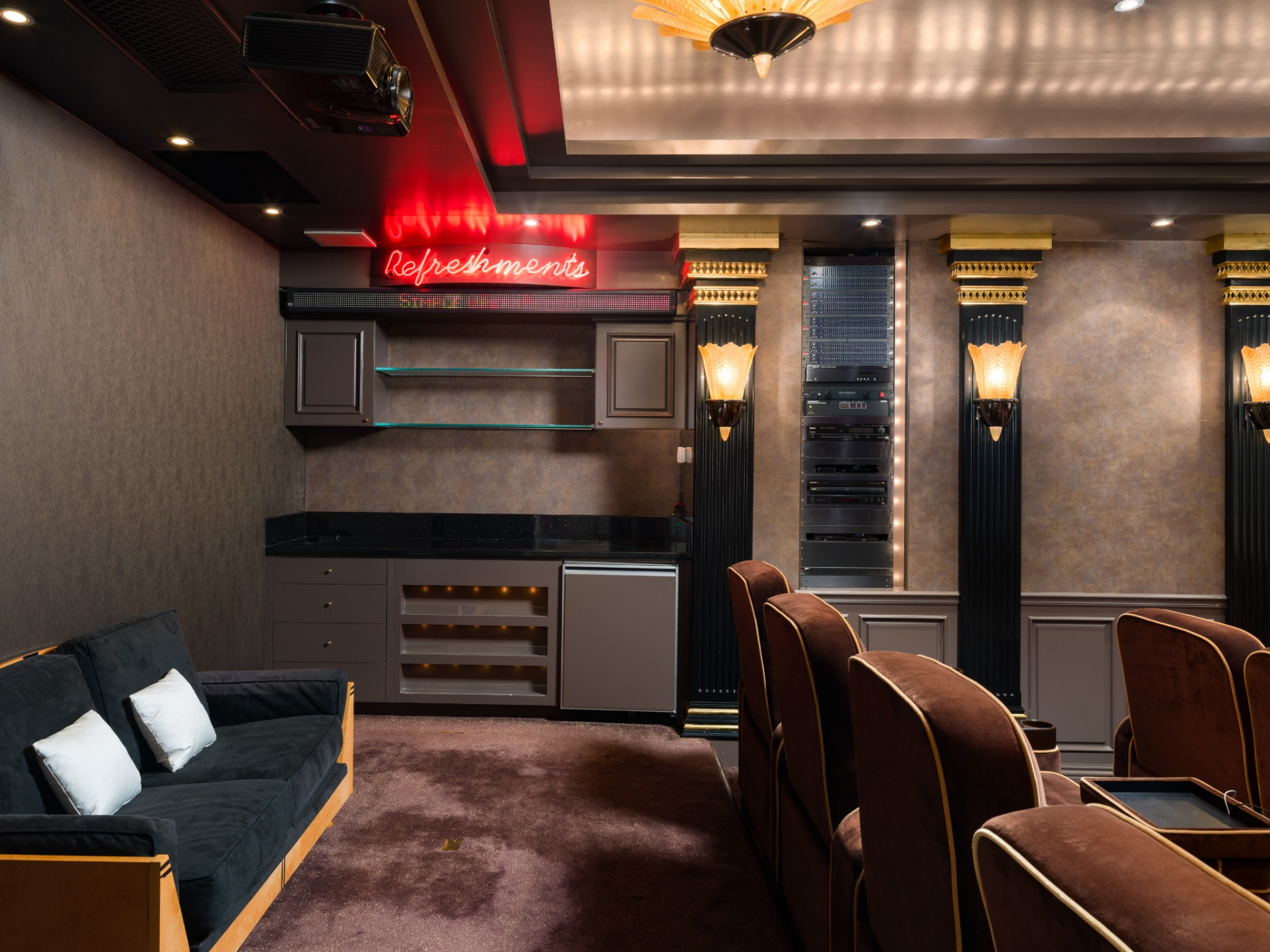 At the back of the room, a built-in concession stand adds its own wine refrigerator, cabinetry, counter space, and shelving beneath a neon “Refreshments” sign.