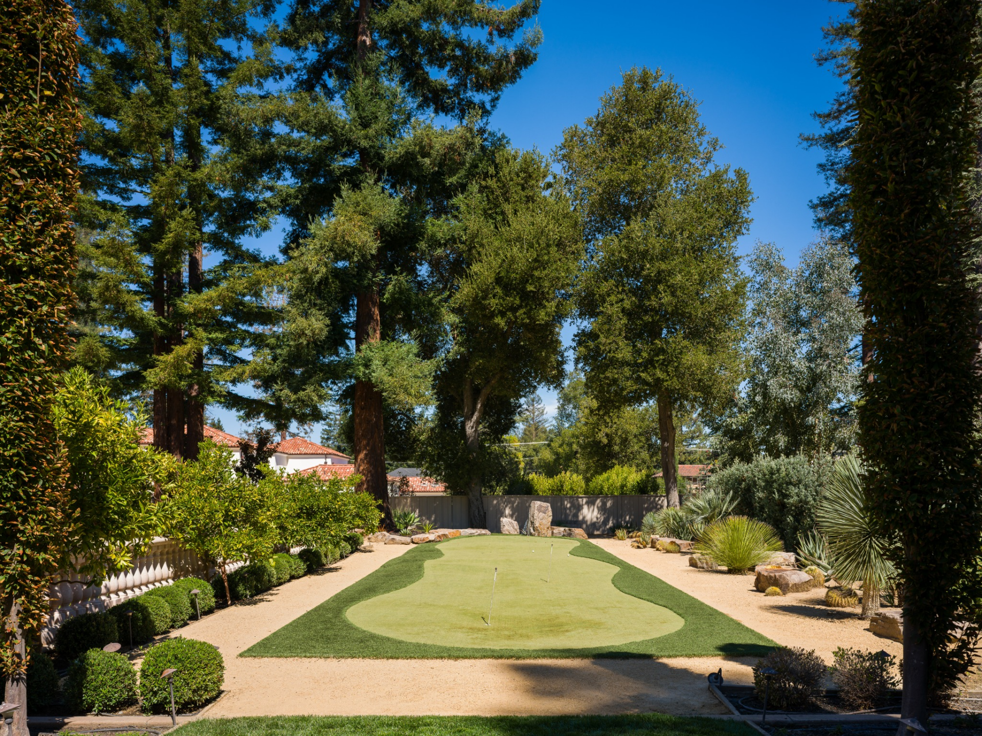 A private putting green stretches between sculpted hedges and drought-tolerant plants