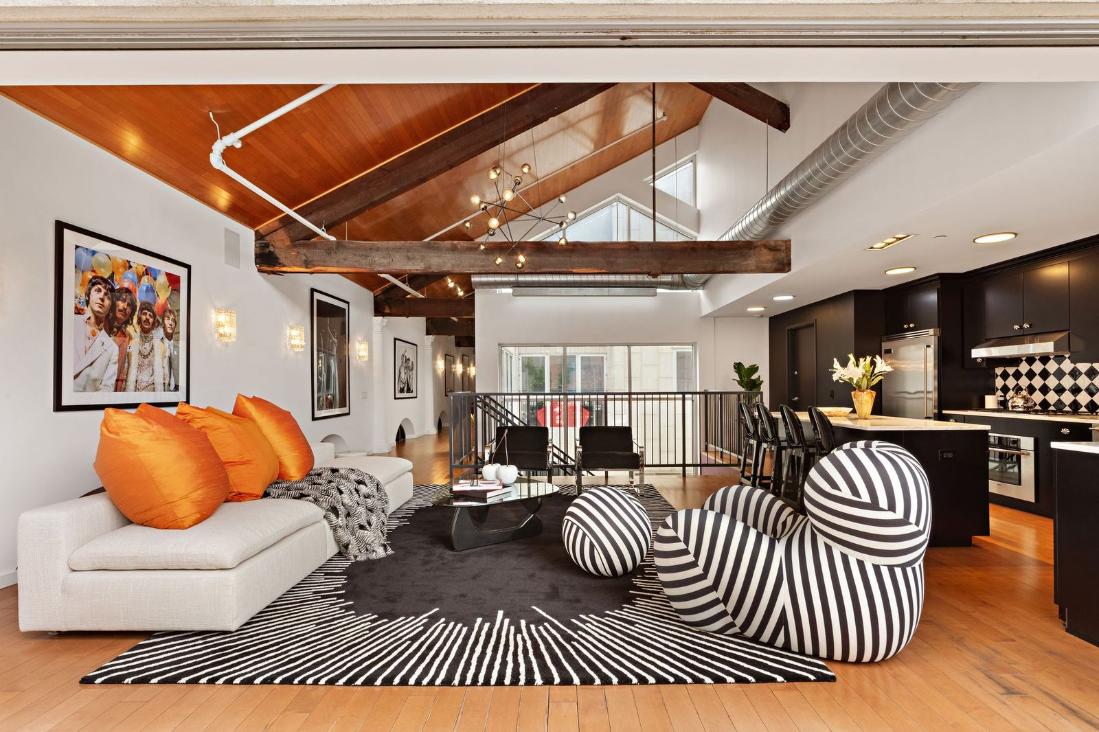 In the living area, the ceiling rises above a grouping of sofas and sculptural chairs arranged around a glass-topped coffee table.
