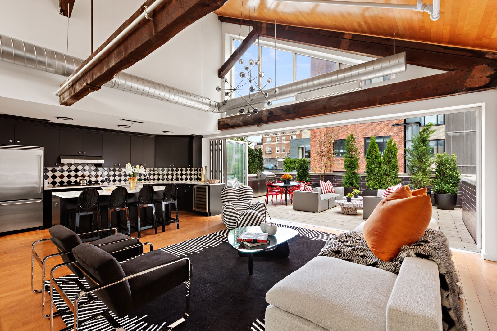 The vaulted ceiling continues into the upper-level main living space, where the living, dining, and kitchen areas are gathered beneath the same exposed beams.