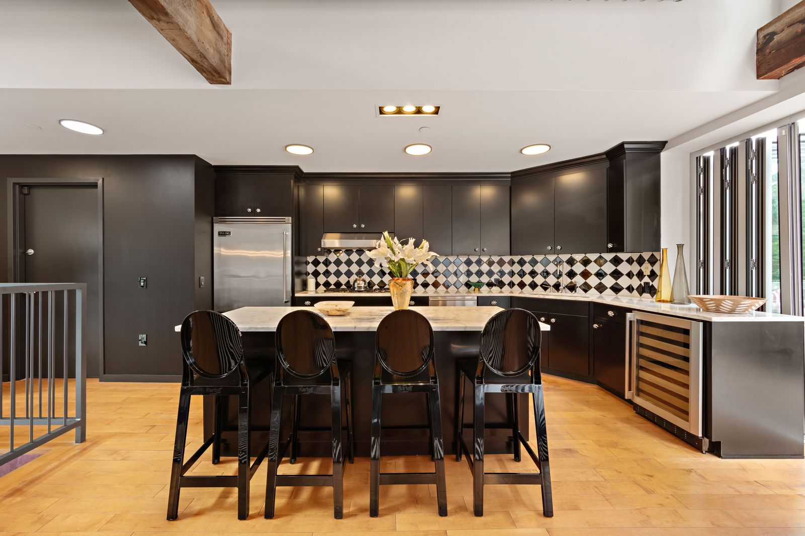 Dark cabinetry wraps the back and side walls around the stainless-steel appliances, while a graphic black-and-white tile backsplash runs continuously behind the work surfaces.
