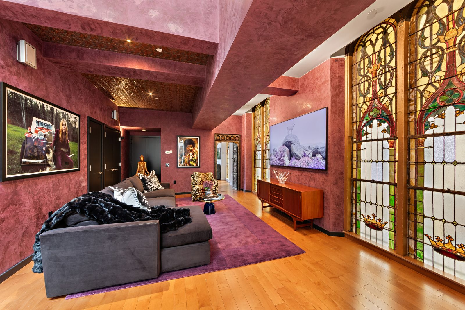 The space has a long sectional facing the TV, which is mounted between panels of stained glass along either side.