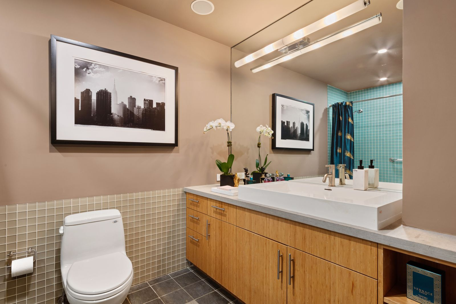 The primary bathroom has a long wood vanity stretches beneath an oversized mirror.