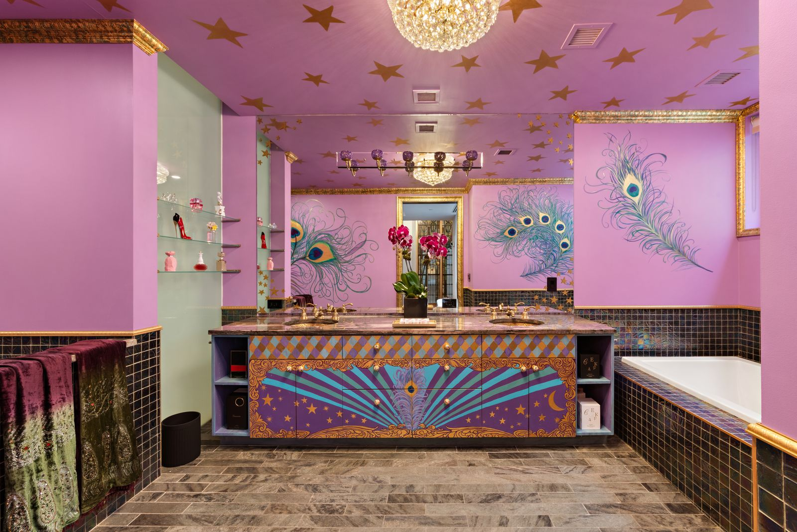 Bathroom with pink painted walls with gold trim, star motifs across the ceiling, and peacock feather artwork around the walls.