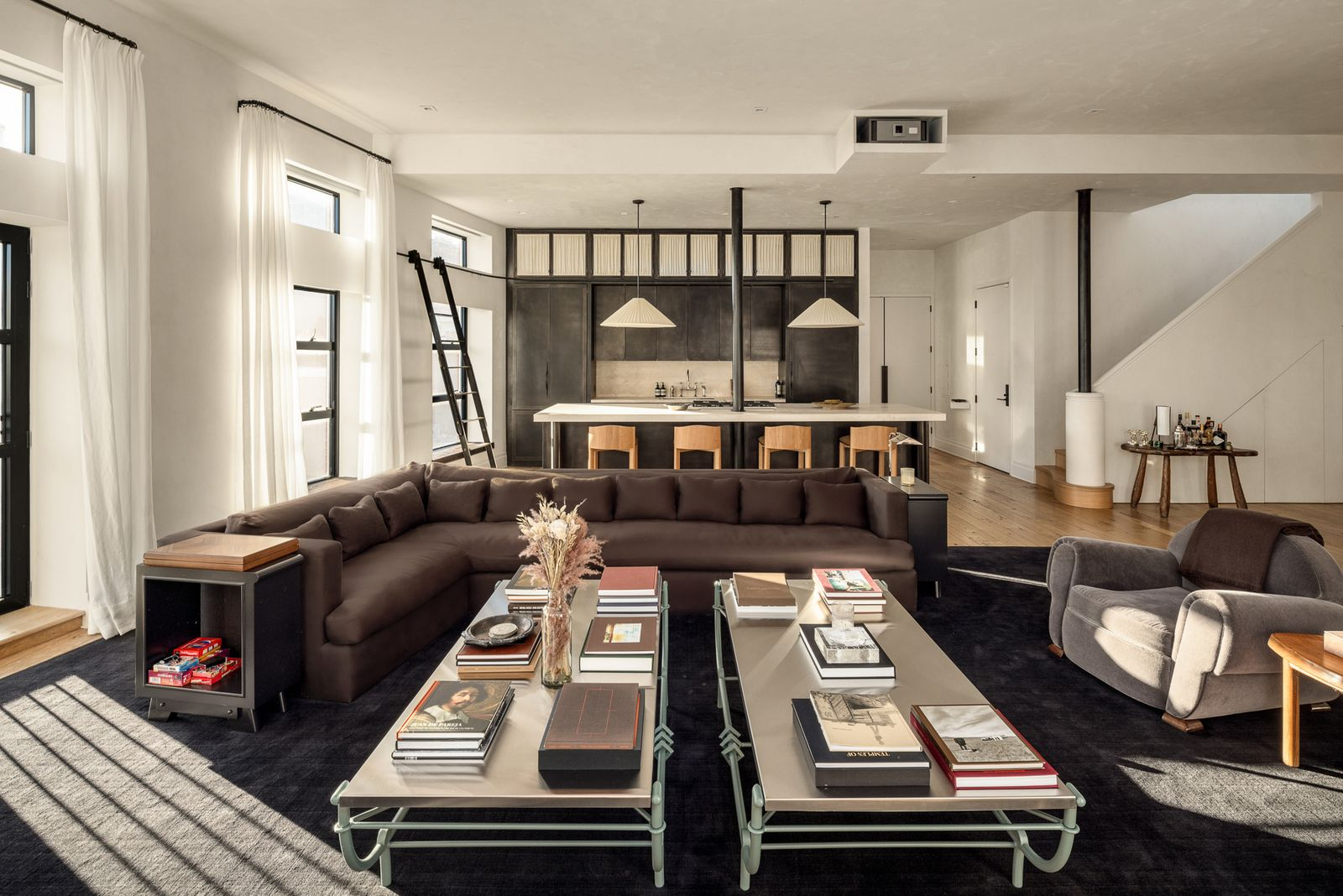 A large brown couch creates the main sitting area around two identical coffee tables stacked with books.