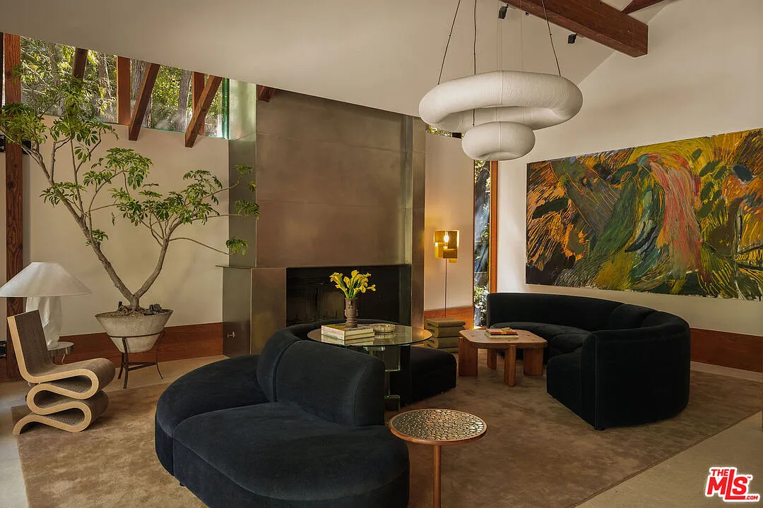 The great room opens beneath exposed wood beams with a fireplace built into one side of the room.