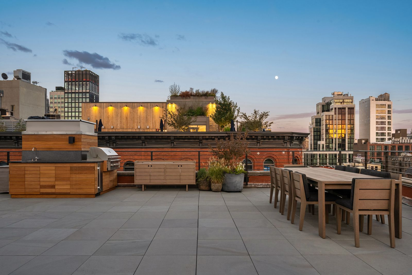 At one end, the terrace has a full outdoor kitchen with built-in cabinetry, a grill, sink, and small refrigerator.