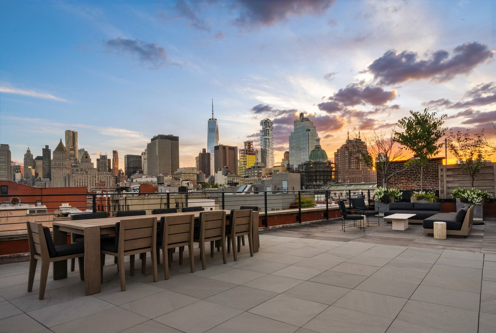 A long dining table sits nearby for larger gatherings, while the opposite end opens to a separate lounge positioned closer to the skyline.