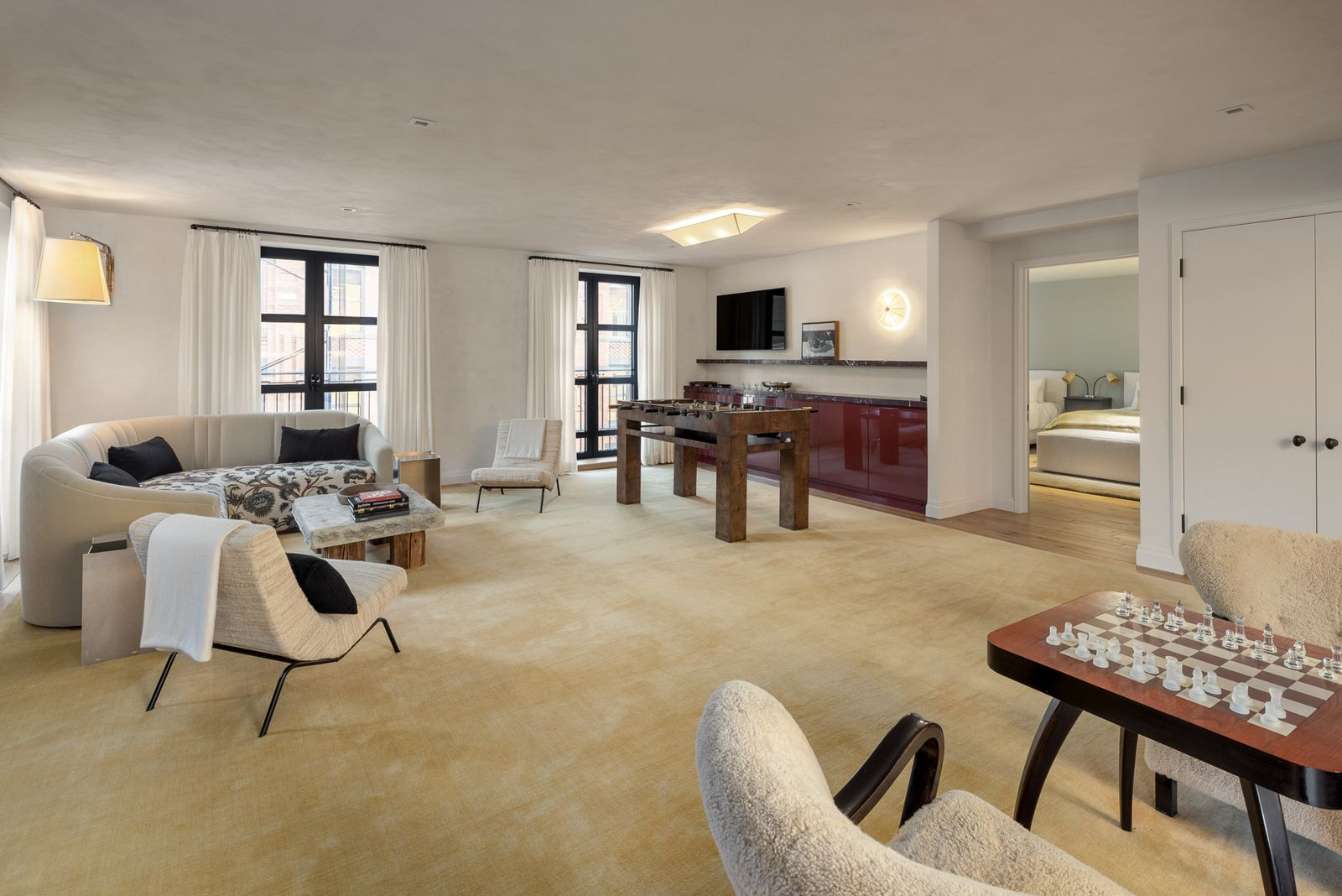 Within the lounge, dark red cabinetry forms a bar in the back corner, while the rest of the room is filled with game tables and several lounge areas.