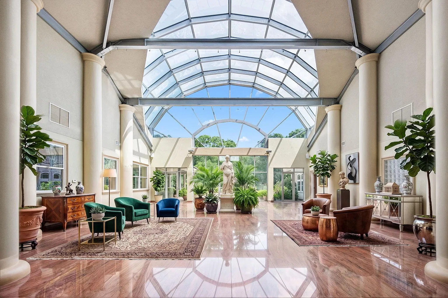 At the center of the home, the layout opens into a sun-filled atrium designed with a steel framework and curved glass ceiling.