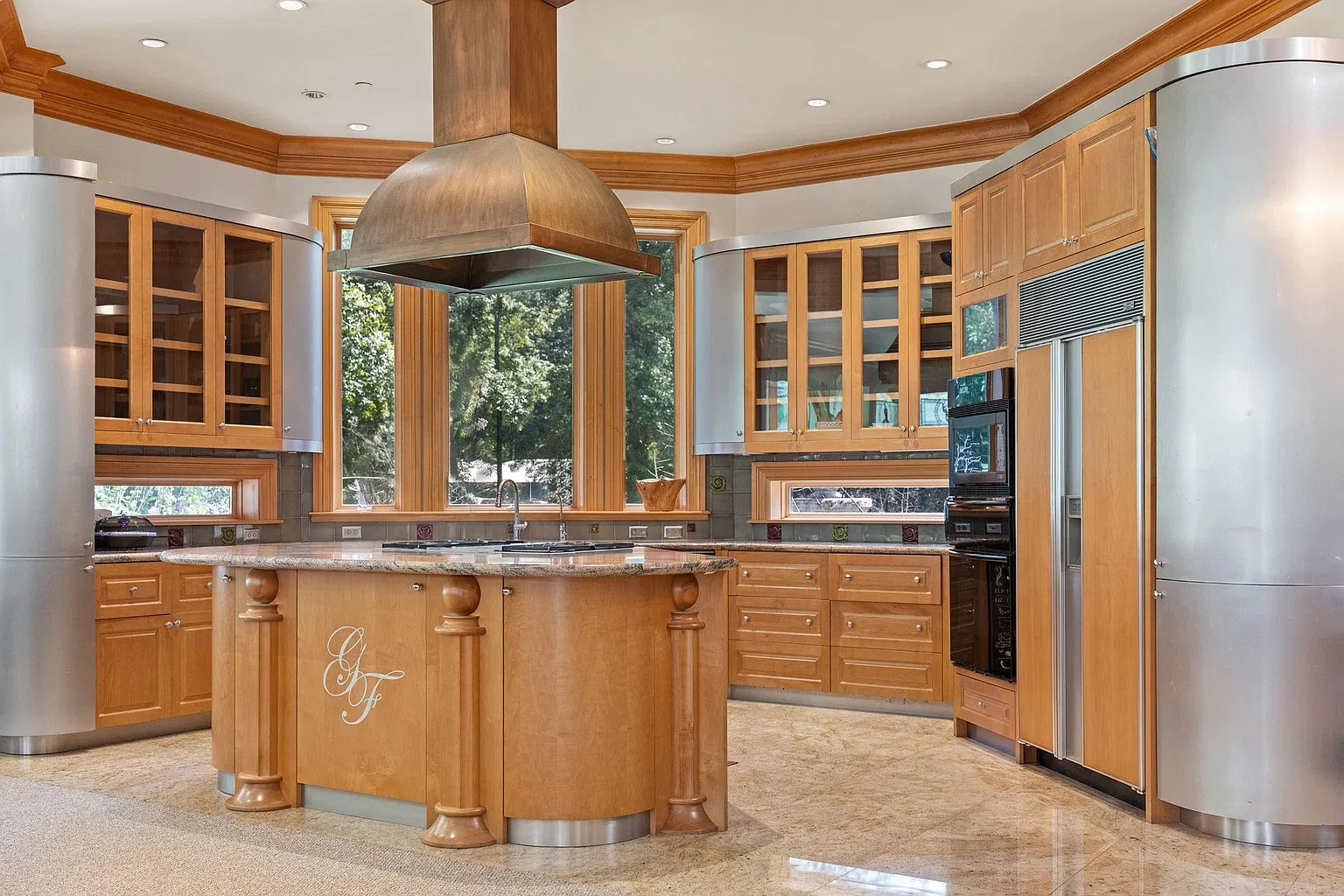 The home's second kitchen with warm wood cabinetry, stainless-steel accents, and a central island with Foreman's initials on the front.
