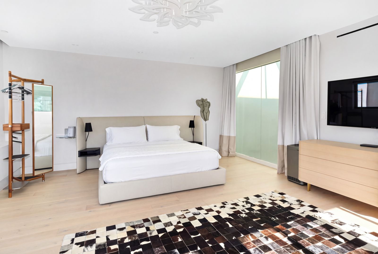 The primary suite bedroom with enough space for a king-size bed, multiple seating areas, and a separate workspace.