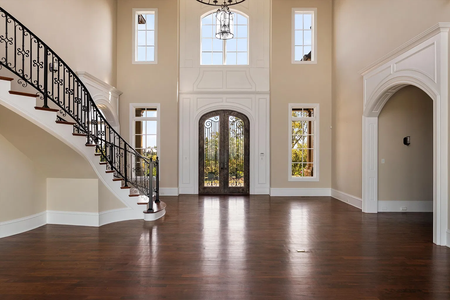 The front door brings you directly into the main level’s great room, where the home’s traditional detailing begins with arched openings, white millwork, and a curved staircase. 