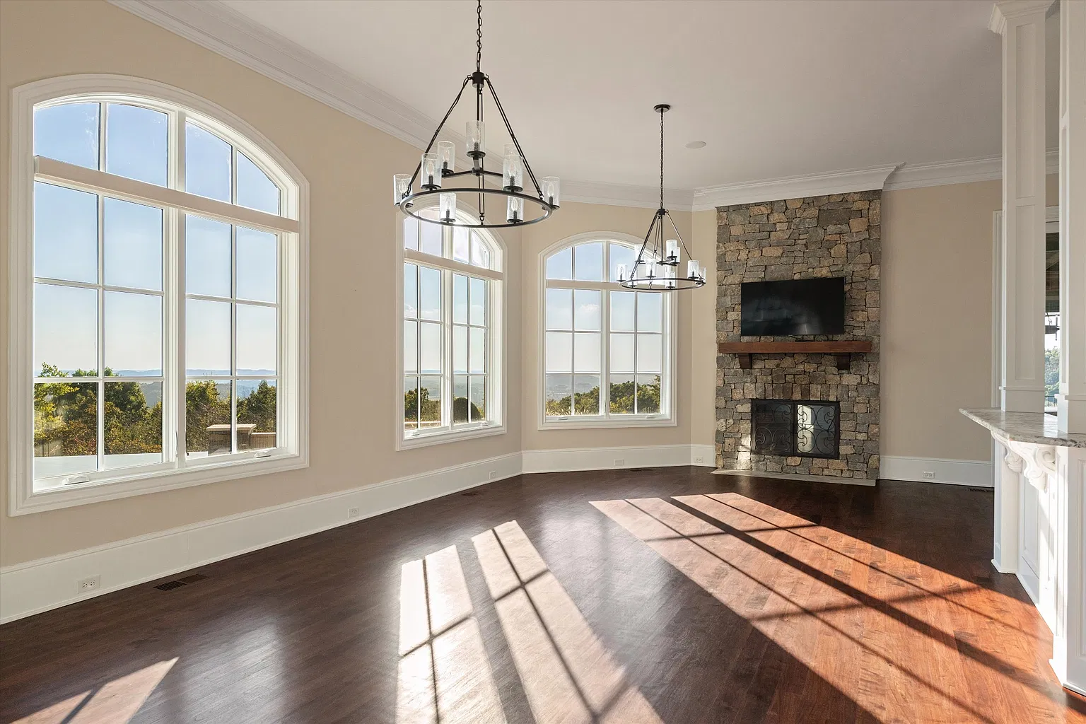 A bar top along the edge of the kitchen opens into an adjoining room lined with tall arched windows. 