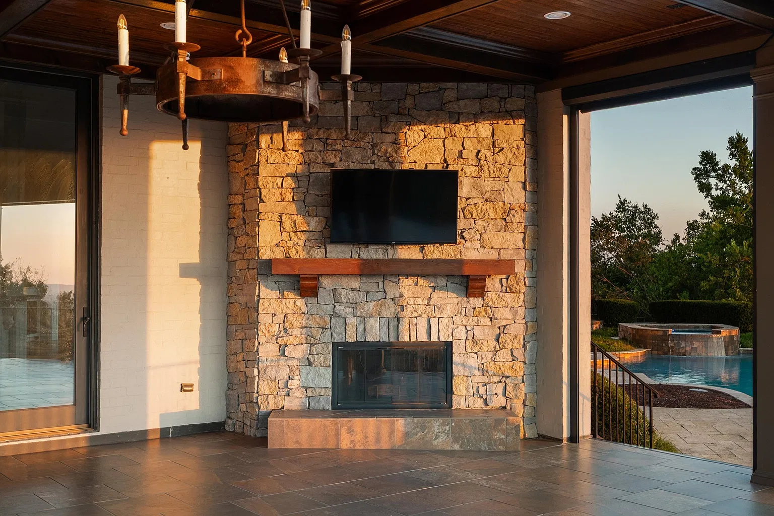 A fireside lounge, where a stone fireplace and mounted TV sit just steps from the cooking area and look out toward the pool.