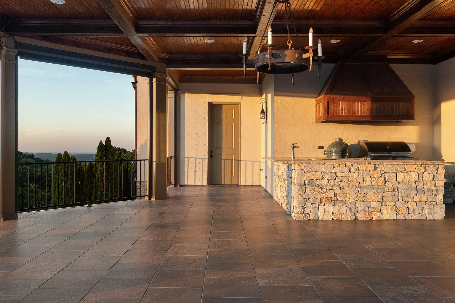 A covered outdoor kitchen set beneath a wood-paneled ceiling. 