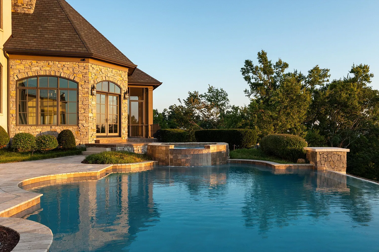 An infinity-edge swimming pool with a raised spa set along one side. 