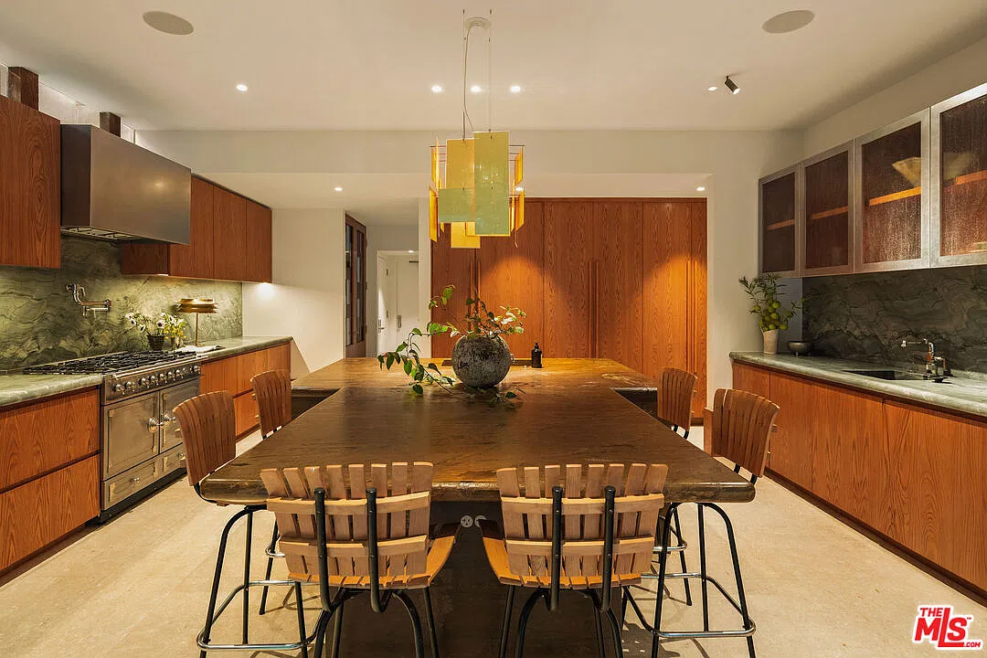 On the left of the island, a La Cornue range sits beneath a wide metal hood, and on the right, a sink sits below upper glass cabinets.