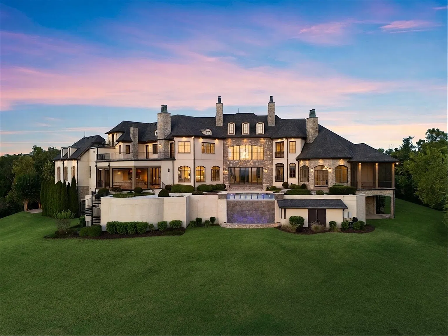 Those outdoor spaces continue well beyond the pool, stepping down to a large lawn that stretches toward the hillside below. 