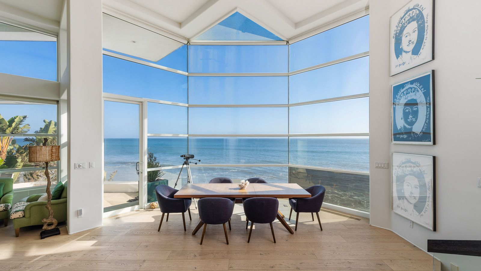 A dining area set directly against a wall of floor-to-ceiling glass for an unobstructed view of the coastline. 
