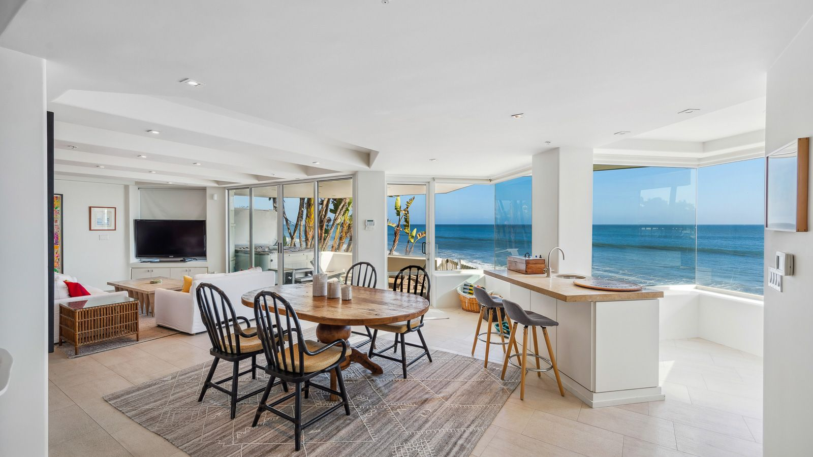 The bottom level opens to a 4-person dining table sitting next to a wet bar with barstools facing the ocean.