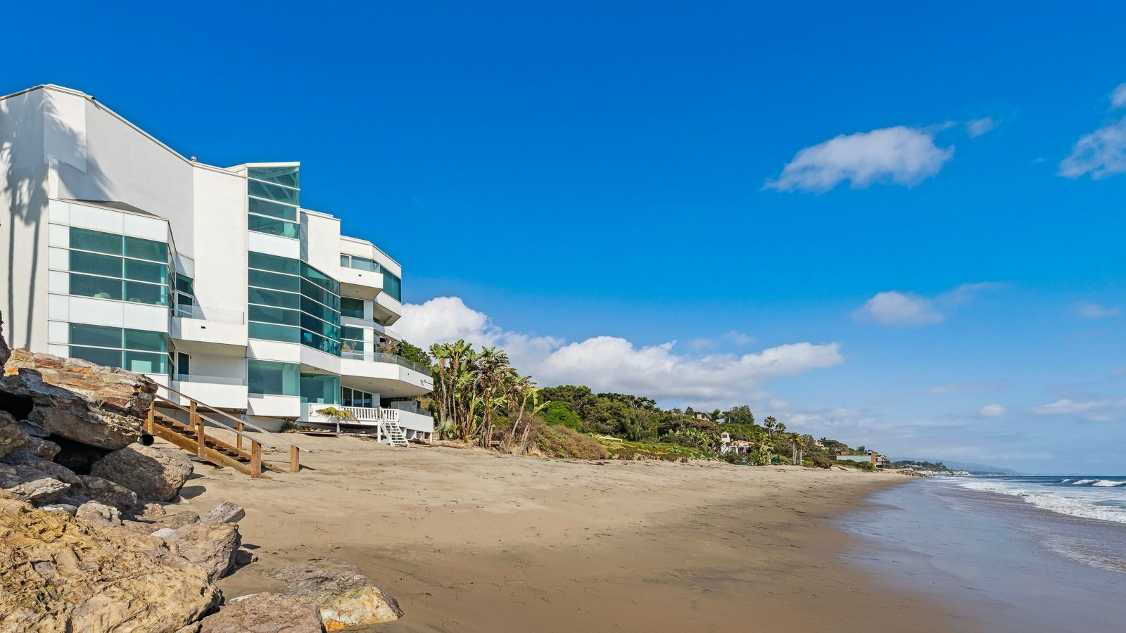 The terrace steps down toward the shoreline to a large stretch of sand and the rolling ocean waves.
