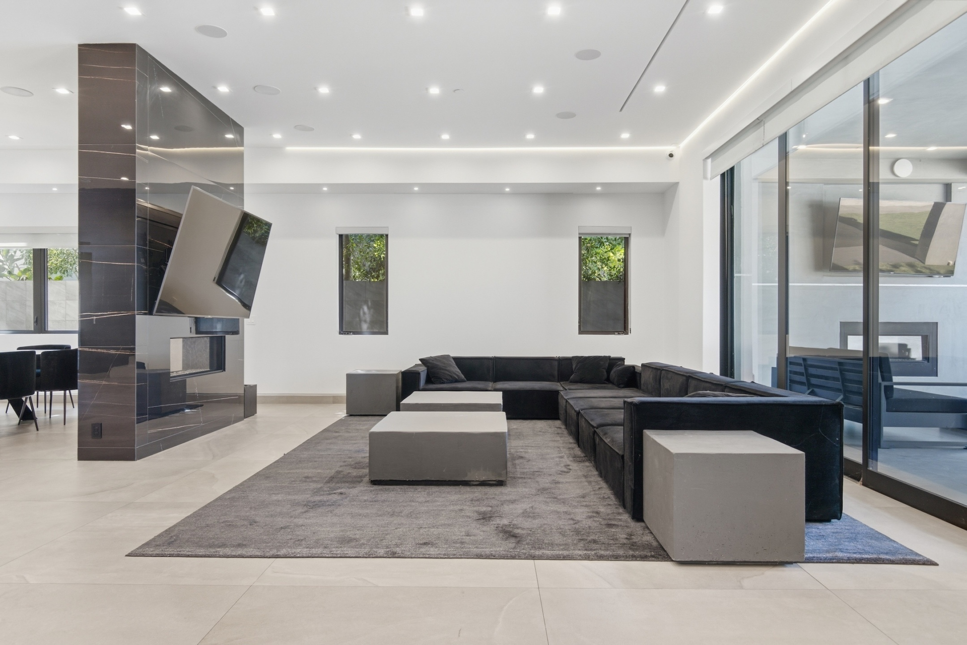 A large sectional wraps around the center of this side of the room, while oversized Fleetwood glass doors line the opposite wall.