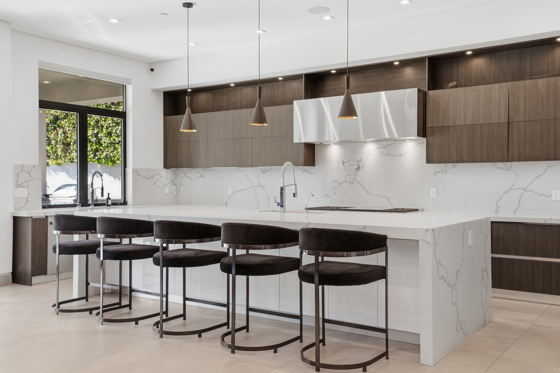 The kitchen is built around an oversized center island, with seating along one side and white stone countertops stretching toward the cooking area.
