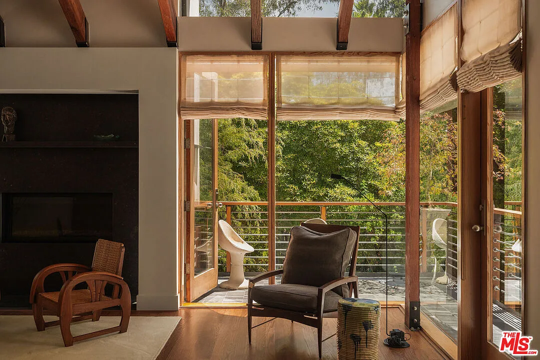 In the corner of the room, glass doors open to a private terrace tucked into the treetops.
