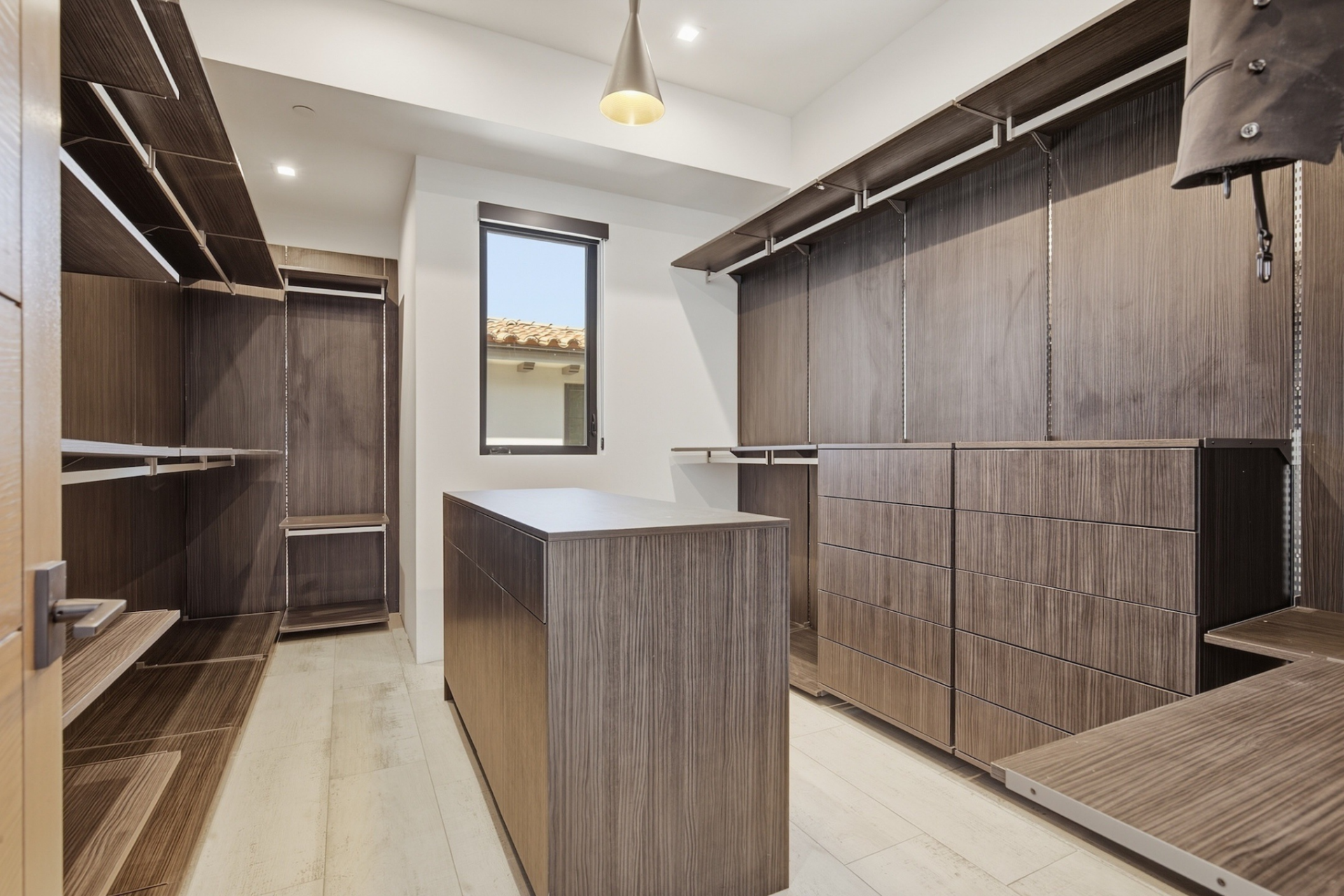 Closet with dark brown wood shelving, hanging storage, and drawers around a central island.