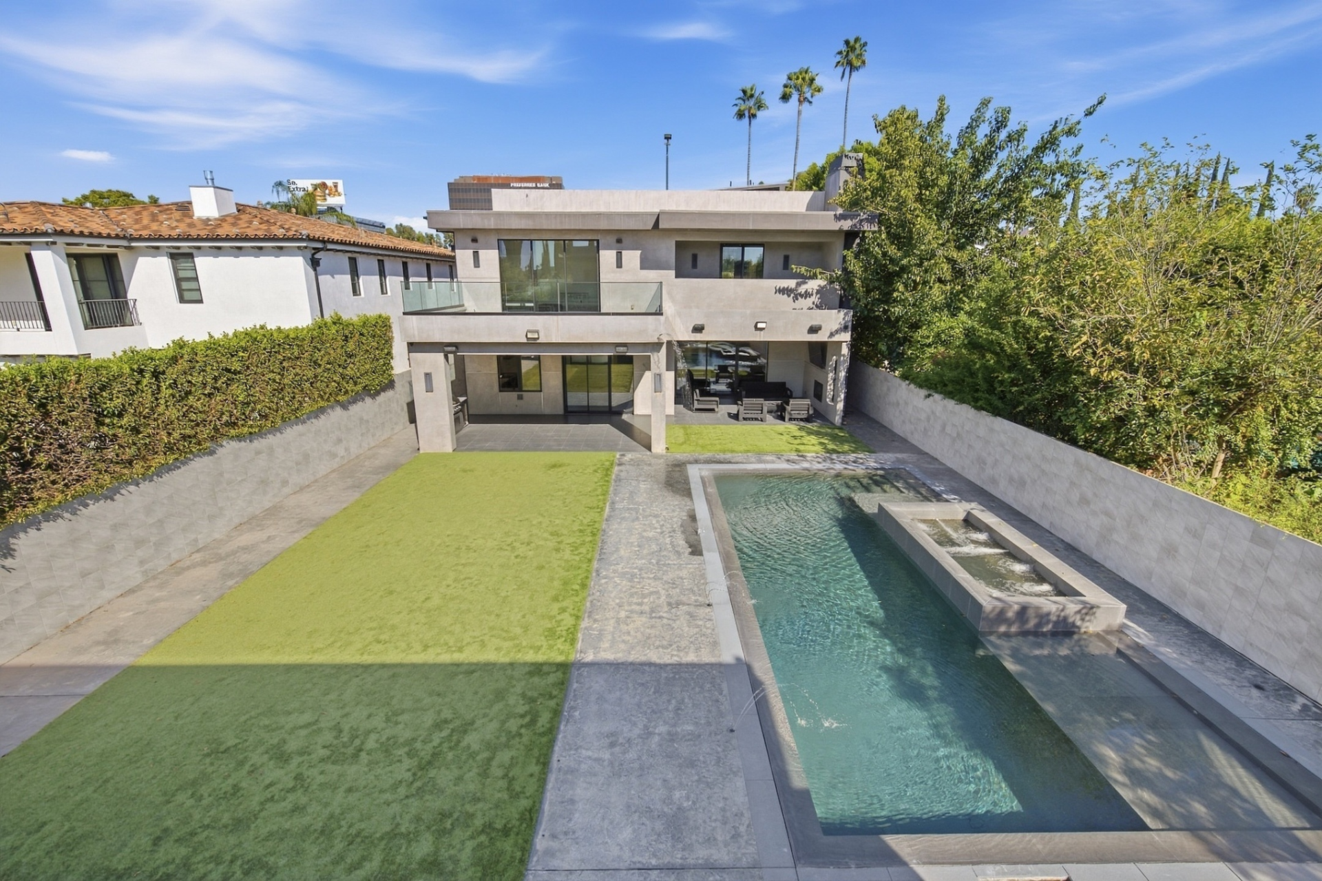 Between the main house and guesthouse, the yard is divided into two long sections with a lawn on one side and a pool on the other.