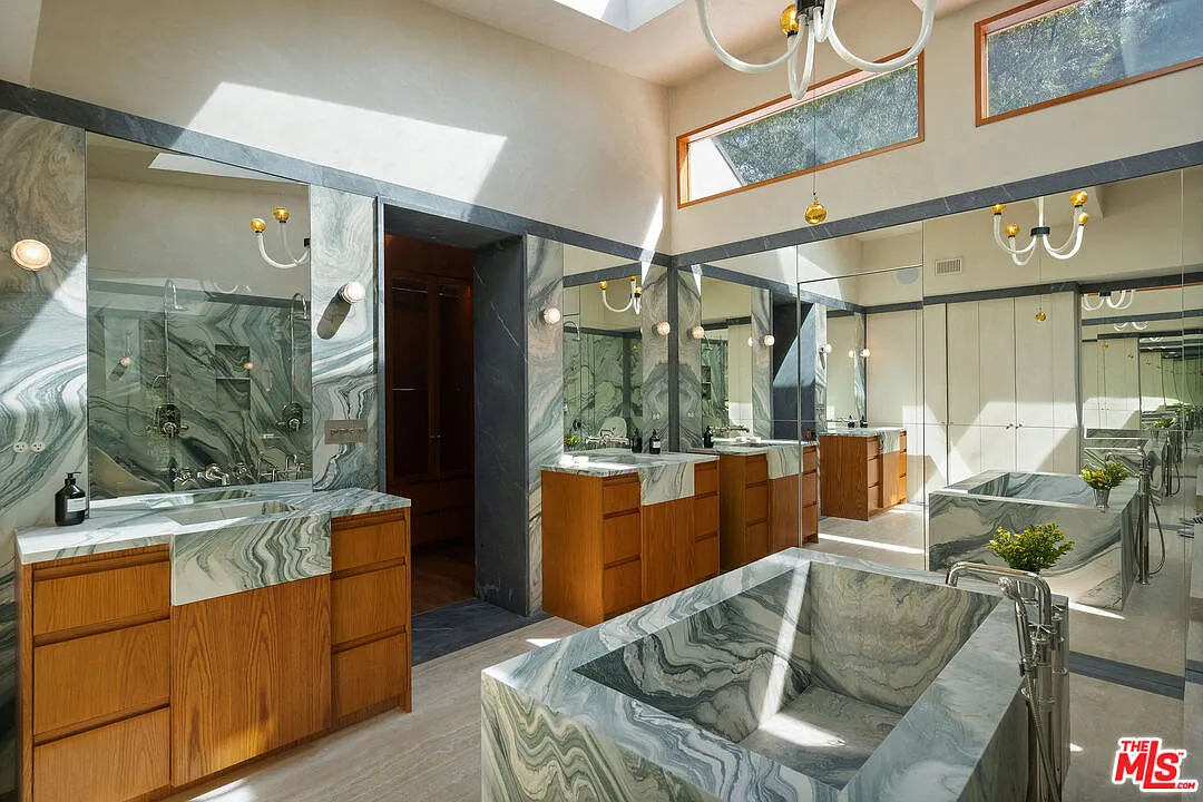 Once inside the bathroom, green marble almost completely takes over, starting with twin vanities that frame the doorway to the dressing room.