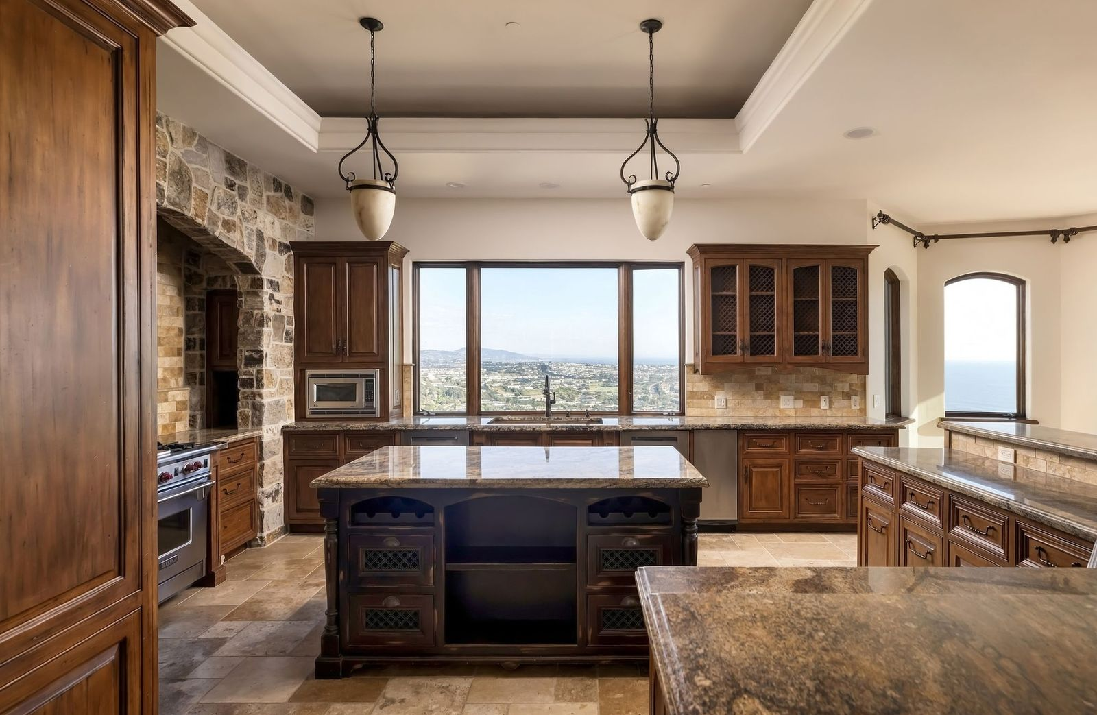 The kitchen is organized around a large center island topped in stone, with dark wood cabinetry wrapping the surrounding walls. 