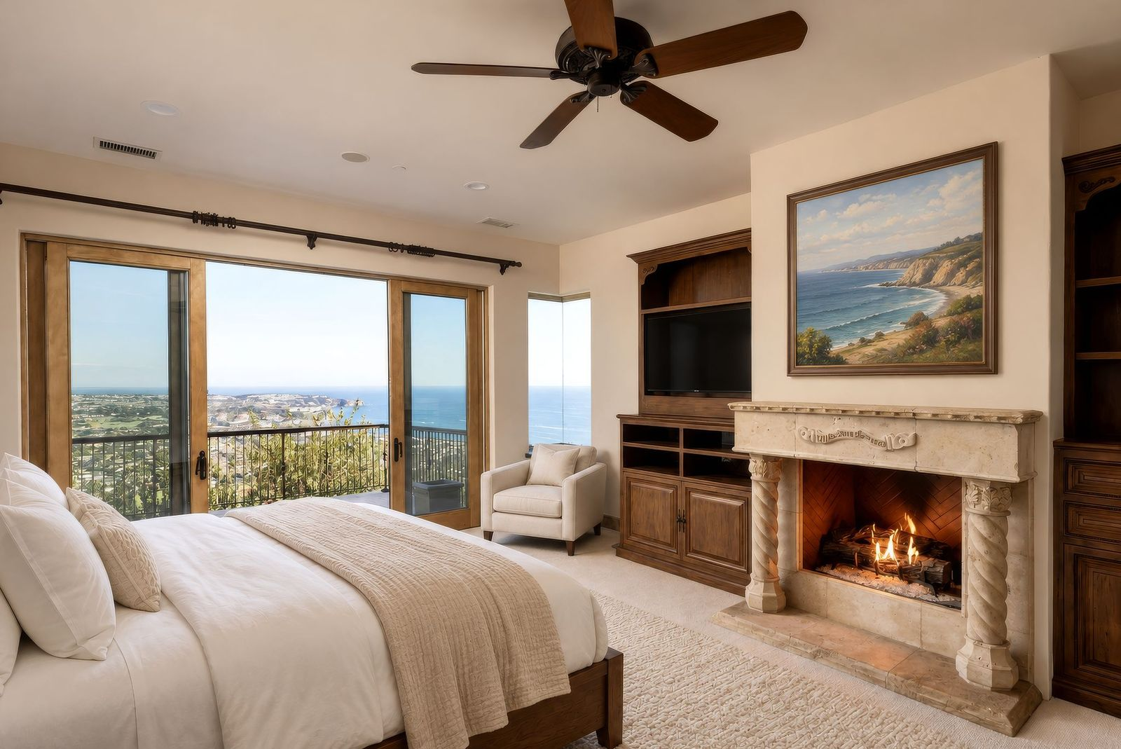 The bedroom arranged around a fireplace and built-in media wall across from the bed with ocean views past the balcony. 